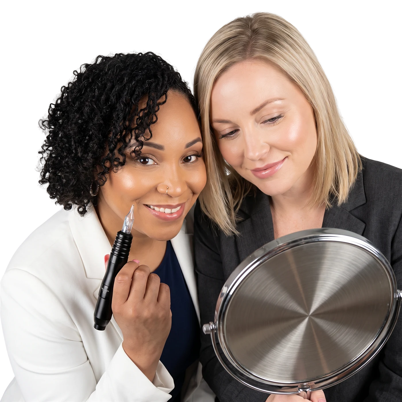 Two permanent makeup artists smiling together, one holding a brow pen and the other looking into a mirror